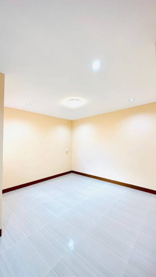 Spacious empty room with white floor tiles and illuminated by ceiling lights