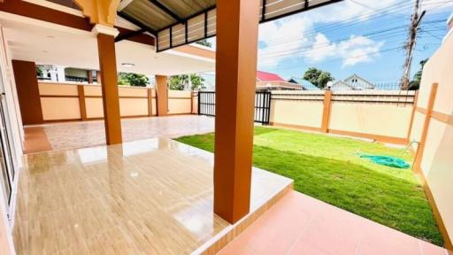 Spacious patio area with glossy tiled flooring and an adjoining grass lawn