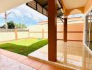 Spacious tiled patio with covered area and adjacent lush green lawn