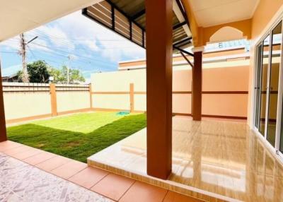 Spacious tiled patio with covered area and adjacent lush green lawn