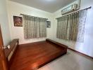 Spacious bedroom with wooden bed frame and air conditioning