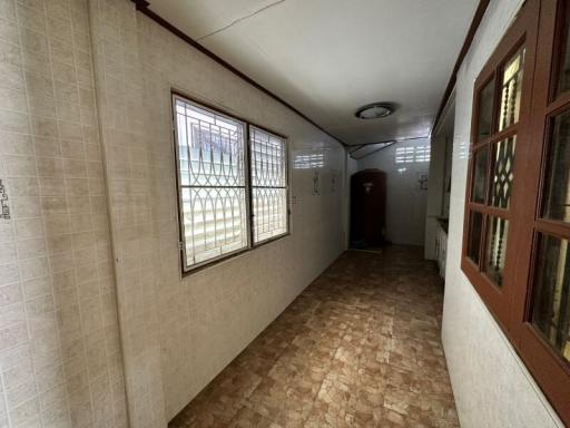 Long narrow hallway with tiled floors and security barred windows