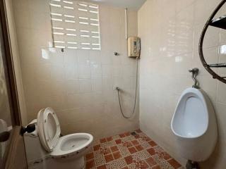 Bathroom with white tiles, toilet, and urinal