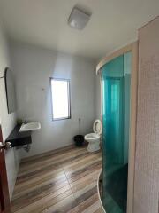 Compact bathroom with wooden flooring, shower cabin, and white fixtures