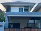 two-story residential house with blue facade and balcony