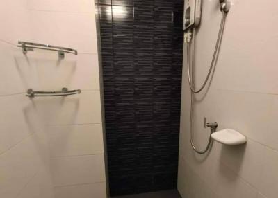 Modern bathroom with wall-mounted shower and black accent tiles