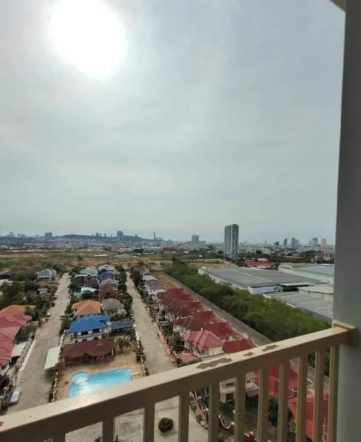 View from balcony overlooking residential area with pool and city skyline in the distance