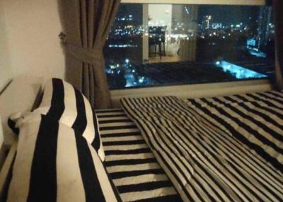 Cozy bedroom interior with striped bedding and night city view through large window