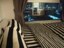 Cozy bedroom interior with striped bedding and night city view through large window