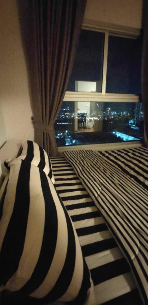 Cozy bedroom interior with striped bedding and night city view through large window