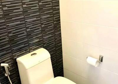 Modern bathroom with a ceramic toilet and decorative tiled wall