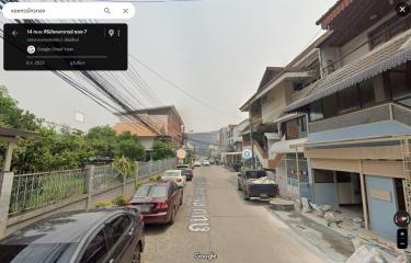 Street view of a residential area with houses and parked cars
