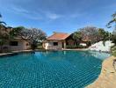 Large swimming pool in front of a residential villa with tropical landscaping