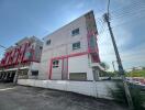 Exterior view of a modern multi-story residential building with white facade and red accents