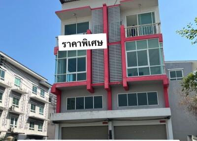 Modern multi-story residential building exterior with balconies and shop space on the ground floor