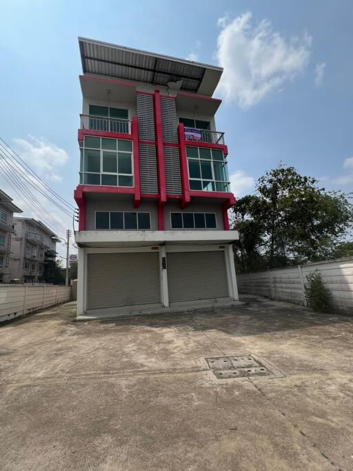 Contemporary three-story building with prominent red accents and garage on the ground floor