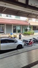 Street view from property showing parking area and commercial establishments