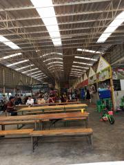 Spacious indoor market with rows of empty benches and various vendor stalls