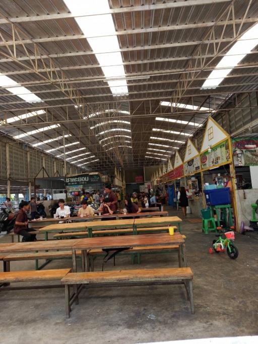 Spacious indoor market with rows of empty benches and various vendor stalls