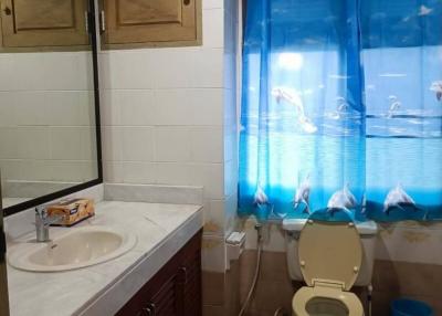 Compact bathroom with blue shower curtain and wooden cabinetry