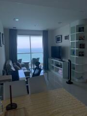 Modern living room with ocean view, furnished with a comfortable seating area, television, and bookshelf