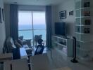 Modern living room with ocean view, furnished with a comfortable seating area, television, and bookshelf