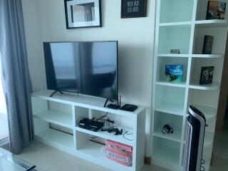 Modern living room with large flat-screen TV and shelving units