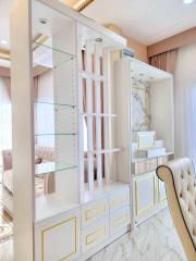 Elegant white-themed living room with glass shelving and modern decor
