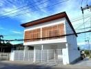 Modern two-story residential building with a white facade and wooden window shutters