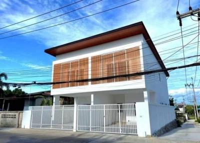 Modern two-story residential building with a white facade and wooden window shutters