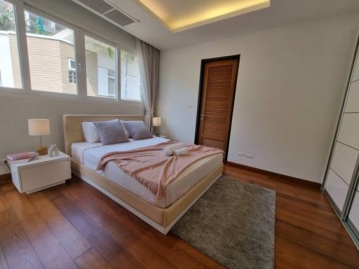 Spacious bedroom with large bed, wood flooring, and ample natural light