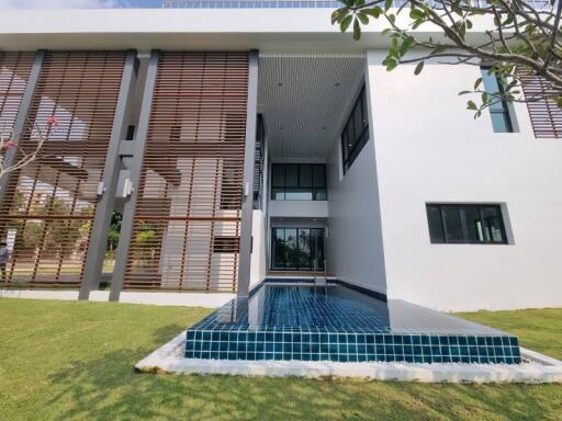 Modern two-story house with exterior wooden slats and a front pool