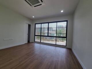 Empty bedroom with wooden floor and large windows