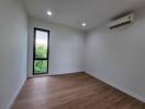 Empty bedroom with large window and air conditioner