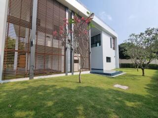 Modern house exterior with lush green lawn and wooden slat privacy screens
