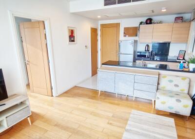 Comfortable living room with modern open kitchen, wooden flooring, and natural light