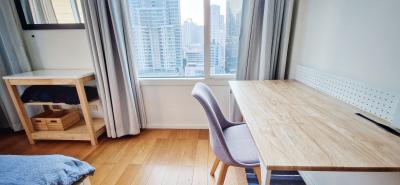 Modern bedroom with city view, work desk, and hardwood flooring