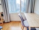 Modern bedroom with city view, work desk, and hardwood flooring