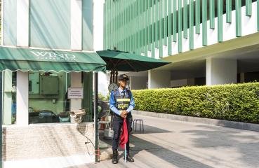 Security guard standing at the building entrance under a shade