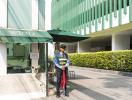 Security guard standing at the building entrance under a shade