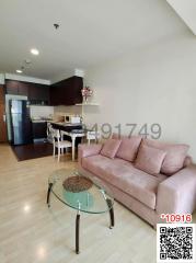 Modern open concept living room with adjoining kitchen, featuring a comfortable sofa and glass coffee table