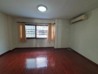 Spacious bedroom with polished wooden floor, air conditioning, and large windows