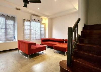 Spacious living room with red sofas and wooden staircase