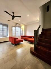 Spacious living room with red sofas and wooden staircase