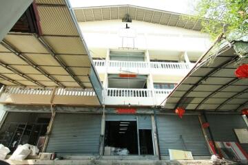 Exterior view of a multi-story building with balconies and closed commercial spaces on the ground floor