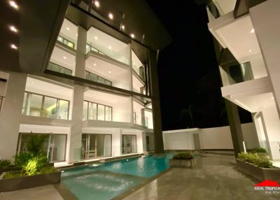 Exterior view of a modern two-story house with pool at night