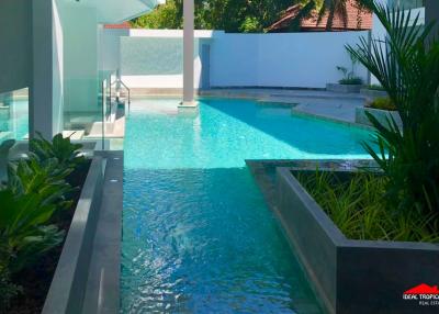 Luxurious outdoor swimming pool surrounded by modern architecture and lush greenery