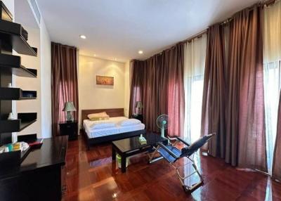 Spacious bedroom with hardwood floors, exercise equipment, and large windows