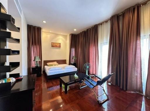 Spacious bedroom with hardwood floors, exercise equipment, and large windows