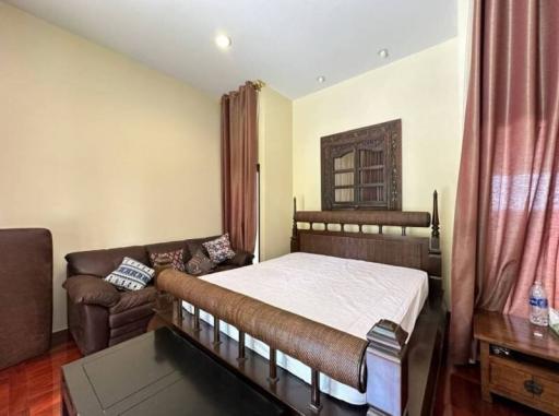 Spacious bedroom with a large bed, comfortable sofa, and wooden furniture